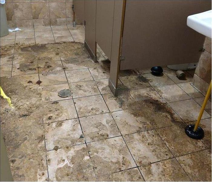 A dirty bathroom floor in a business that suffered a leak